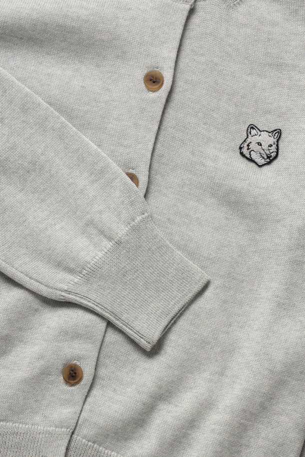 **BOLD FOX HEAD PATCH REGULAR CARDIGAN - LIGHT GREY MELANGE**는 울 소재의 남녀 공용 니트/스웨터 카디건입니다. 라이트 그레이 멜란지 컬러에, 라운드넥과 레귤러핏, 긴소매 기장으로 봄, 가을철에 착용하기 좋습니다. 가슴 부분 메종키츠네 자수 패치워크와 버튼 잠금, 네크라인, 허리, 커프스 부분의 리브 디테일이 특징입니다.
