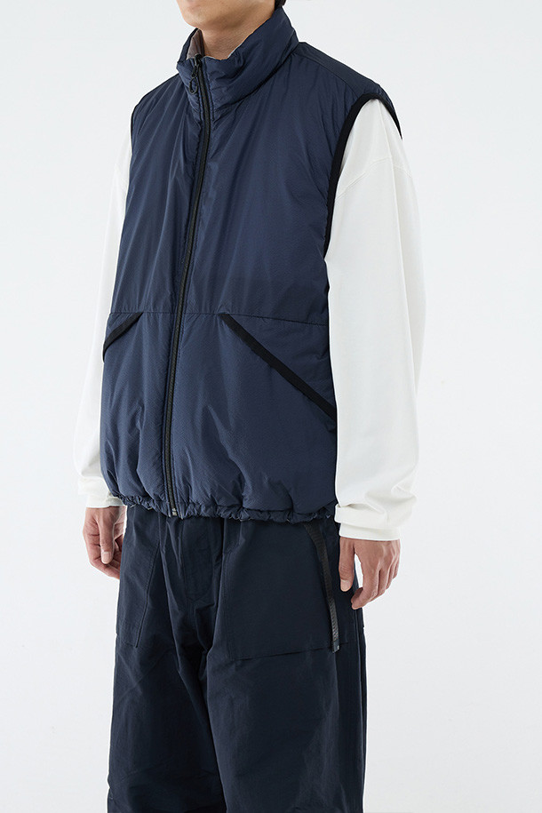 **REVERSIBLE PUFF VEST - CLOUD GRAY/NAVY (리버서블 패딩 베스트 - 클라우드 그레이/네이비)**

클라우드 그레이와 네이비 컬러 양면으로 착용 가능한 남성용 리버서블 패딩 베스트입니다. 가을, 겨울 시즌에 적합하며, 캐주얼 및 스포티 스타일을 연출할 수 있습니다. 넉넉한 루즈핏으로 편안한 착용감을 제공하며, 지퍼형 여밈과 스탠드 카라 디자인으로 보온성을 높였습니다. 방수, 보온, 통기 기능에 신슐레이트 충전재를 사용하여 한겨울에도 따뜻하게 입을 수 있습니다. 일상, 산책, 여행 등 다양한 TPO에 활용하기 좋은 아이템입니다.
