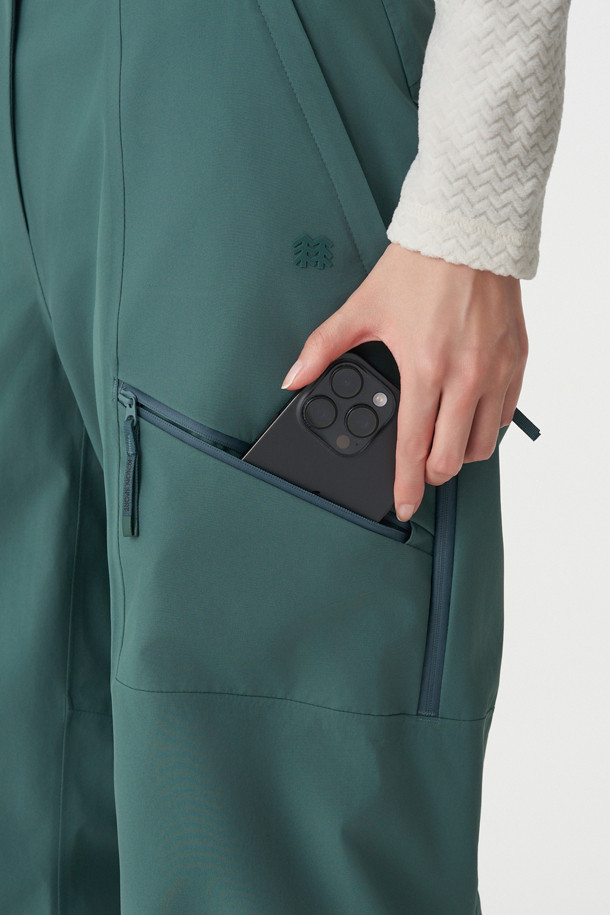 겨울 하이킹, 캠핑 등 아웃도어 활동에 적합한 여성 방수 팬츠입니다. 그린 컬러의 무지 디자인으로 스포티, 고프코어, 미니멀 스타일을 연출할 수 있습니다. 3L 방수 원단에 전체 심실링 마감 처리하여 뛰어난 방수, 방풍, 발수 기능을 제공합니다. 무릎 입체 절개 패턴과 허리 이밴드 및 스트링으로 편안한 착용감을 선사하며, 허벅지와 종아리 지퍼 디테일로 활동성을 높였습니다. 레귤러핏의 긴 기장으로 겨울철 보온성을 유지하며, 밴딩 처리로 활동성을 더했습니다.
