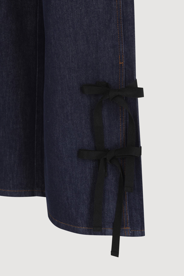 럭키슈에뜨 Side Ribbon Wide Denim Pants (dark blue)는 여성용 와이드핏 데님 팬츠입니다. 양 사이드 리본 디테일과 럭키슈에뜨 로고 캔톤, 리벳 장식, 뒤 포켓 개발 스티치 자수가 특징이며, 캐주얼 및 스트릿 스타일 연출에 용이합니다. 봄, 여름, 가을 시즌 일상복으로 활용하기 좋으며, 맥시 기장의 다크 블루 컬러 데님 소재로 제작되었습니다.
