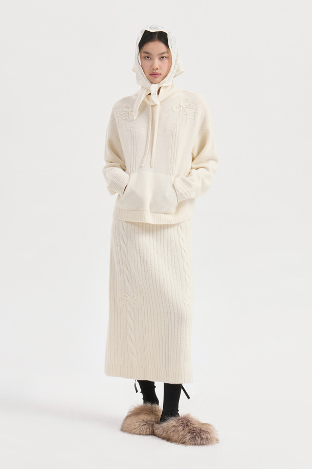 **Ribbon Knit Skirt (아이보리)**

부드러운 메리노울 소재의 리본 니트 스커트입니다. 세미 A라인 핏과 맥시 기장으로 우아한 실루엣을 연출하며, 케이블 및 립조직 패턴이 고급스러운 분위기를 더합니다. 밑단 립조직과 리본 디테일이 돋보이며, 두꺼운 두께감으로 따뜻하게 착용 가능합니다. 가을, 겨울 시즌 데이트룩, 모임룩, 출근룩 등 다양한 TPO에 활용 가능하며, 클래식, 미니멀, 걸리시 스타일을 즐기는 여성분들께 추천합니다. 체형 커버에도 효과적이며 세트업으로도 활용할 수 있습니다.
