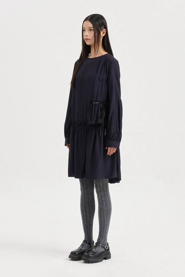 다크 네이비 컬러의 셔링 디테일 라운드넥 원피스입니다. 부드러운 레이온 소재로 제작되어 편안한 착용감을 선사하며, 루즈핏과 플레어 A라인 치마가 자연스러운 실루엣을 연출합니다. 허리선 아래 셔링으로 볼륨감을 더하고, 허리 부분 로고 테이프로 포인트를 주었습니다. 긴 소매와 뒷넥 단추 여밈으로 클래식하면서도 캐주얼한 분위기를 자아내 데이트룩, 모임룩, 또는 미니멀한 스타일을 연출하고 싶은 날에 적합합니다. 사계절 내내 활용 가능한 실용적인 아이템입니다.
