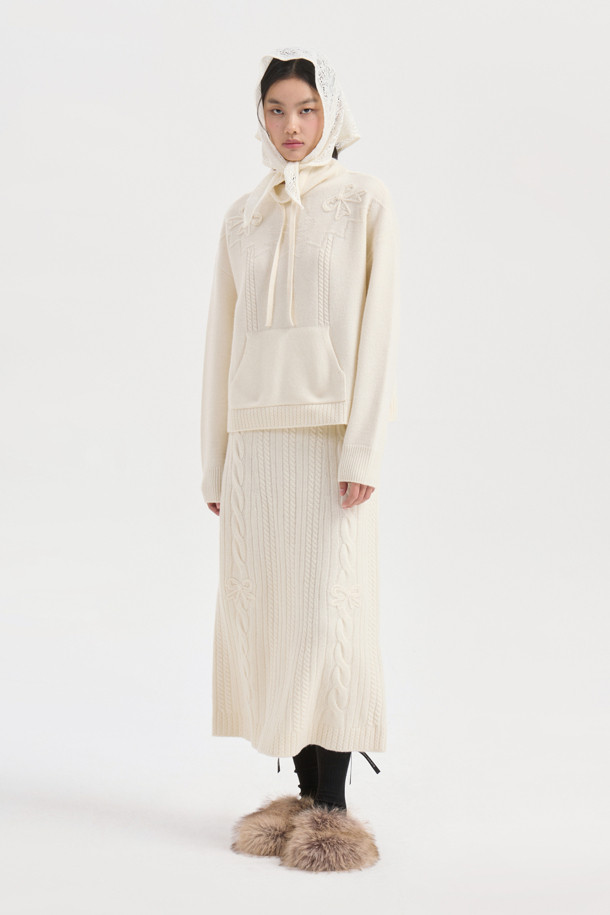 **Ribbon Knit Skirt (아이보리)**

부드러운 메리노울 소재의 리본 니트 스커트입니다. 세미 A라인 핏과 맥시 기장으로 우아한 실루엣을 연출하며, 케이블 및 립조직 패턴이 고급스러운 분위기를 더합니다. 밑단 립조직과 리본 디테일이 돋보이며, 두꺼운 두께감으로 따뜻하게 착용 가능합니다. 가을, 겨울 시즌 데이트룩, 모임룩, 출근룩 등 다양한 TPO에 활용 가능하며, 클래식, 미니멀, 걸리시 스타일을 즐기는 여성분들께 추천합니다. 체형 커버에도 효과적이며 세트업으로도 활용할 수 있습니다.
