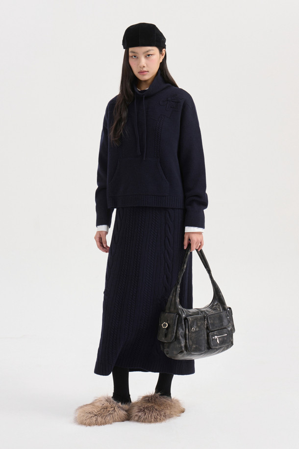 다크 네이비 색상의 리본 니트 스커트입니다. 메리노 울 소재로 제작되어 부드러운 촉감과 따뜻함을 선사하며, 가을/겨울 시즌에 적합합니다. 세미 A라인 핏에 밑단 립조직과 케이블/립조직 패턴이 우아하고 클래식한 분위기를 연출합니다. 허리 부분의 리본 디테일이 여성스러운 포인트를 더하며, 체형 커버에도 효과적입니다. 출근룩과 모임룩 모두 소화 가능한 활용도 높은 맥시 스커트로, 셋업 연출도 가능합니다.
