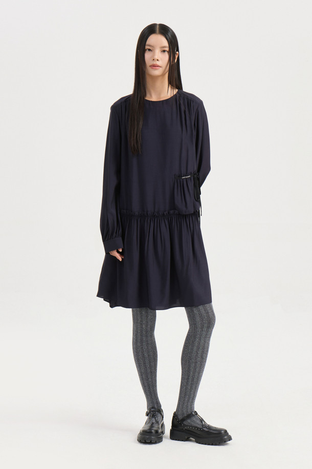 다크 네이비 컬러의 셔링 디테일 라운드넥 원피스입니다. 부드러운 레이온 소재로 제작되어 편안한 착용감을 선사하며, 루즈핏과 플레어 A라인 치마가 자연스러운 실루엣을 연출합니다. 허리선 아래 셔링으로 볼륨감을 더하고, 허리 부분 로고 테이프로 포인트를 주었습니다. 긴 소매와 뒷넥 단추 여밈으로 클래식하면서도 캐주얼한 분위기를 자아내 데이트룩, 모임룩, 또는 미니멀한 스타일을 연출하고 싶은 날에 적합합니다. 사계절 내내 활용 가능한 실용적인 아이템입니다.
