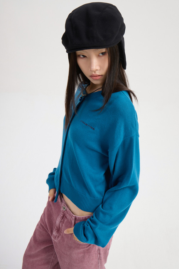 럭키슈에뜨의 Chouetties(슈에티) 언밸런스 니트 가디건 (블루)입니다. 아크릴과 코튼 혼방 소재로 제작되어 부드러운 촉감을 자랑하며, 가을, 겨울 시즌에 따뜻하게 착용할 수 있습니다. 캐주얼 스타일의 라운드넥 긴소매 가디건으로, 언밸런스한 기장감과 레터링 패턴이 특징입니다. 세 가지 모양의 믹스 단추 디테일이 돋보이며, 루즈핏으로 편안하게 착용 가능한 데일리 아이템입니다.
