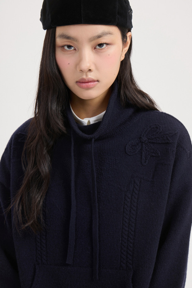 다크 네이비 색상의 리본 니트 풀오버는 여성스러운 무드를 연출하는 상의입니다. 메리노 울 100% 소재로 제작되어 부드러운 촉감과 뛰어난 보온성을 자랑하며, 넉넉한 루즈핏으로 편안하게 착용 가능합니다. 후드 디자인과 캥거루 포켓, 소매의 긴 기장이 캐주얼한 스타일을 더하고, 리본 디테일이 사랑스러운 포인트를 더합니다. 스트링 조절이 가능하여 핏을 조절할 수 있으며, 가을, 겨울철 일상룩, 집콕룩, 산책룩, 여행룩에 활용하기 좋습니다. 베이직하면서도 미니멀, 클래식한 스타일을 즐기는 분들께 추천합니다.
