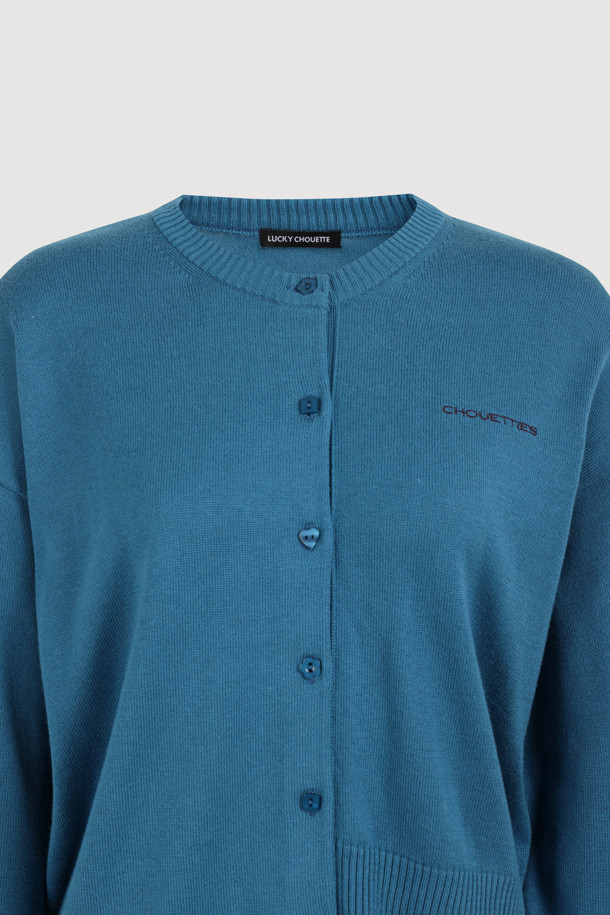 럭키슈에뜨의 Chouetties(슈에티) 언밸런스 니트 가디건 (블루)입니다. 아크릴과 코튼 혼방 소재로 제작되어 부드러운 촉감을 자랑하며, 가을, 겨울 시즌에 따뜻하게 착용할 수 있습니다. 캐주얼 스타일의 라운드넥 긴소매 가디건으로, 언밸런스한 기장감과 레터링 패턴이 특징입니다. 세 가지 모양의 믹스 단추 디테일이 돋보이며, 루즈핏으로 편안하게 착용 가능한 데일리 아이템입니다.
