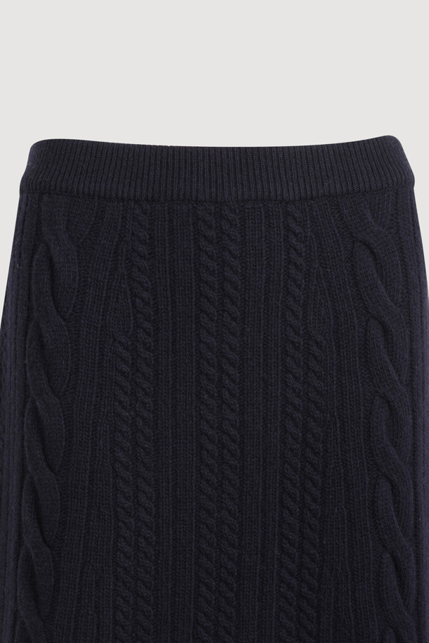 다크 네이비 색상의 리본 니트 스커트입니다. 메리노 울 소재로 제작되어 부드러운 촉감과 따뜻함을 선사하며, 가을/겨울 시즌에 적합합니다. 세미 A라인 핏에 밑단 립조직과 케이블/립조직 패턴이 우아하고 클래식한 분위기를 연출합니다. 허리 부분의 리본 디테일이 여성스러운 포인트를 더하며, 체형 커버에도 효과적입니다. 출근룩과 모임룩 모두 소화 가능한 활용도 높은 맥시 스커트로, 셋업 연출도 가능합니다.
