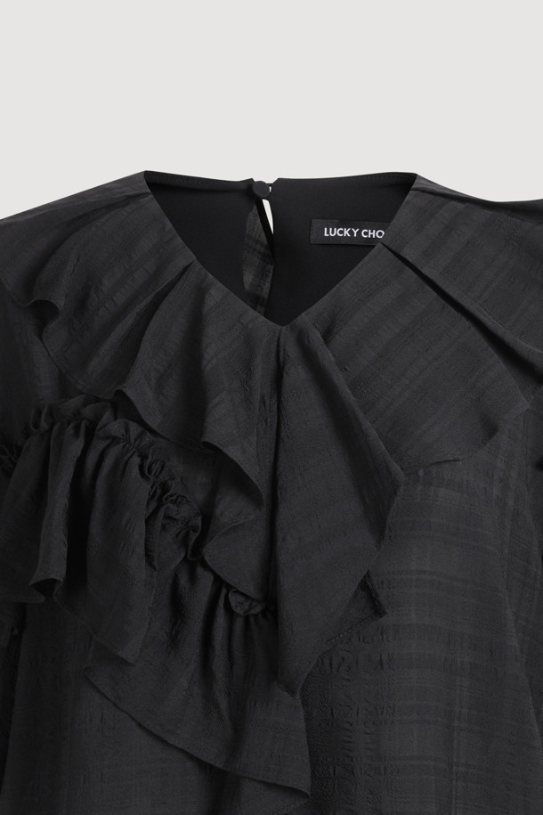 **러플 포인트 체크 블라우스 (블랙)**

페미닌한 무드의 여성 블라우스입니다. 봄, 여름 시즌에 어울리는 얇은 두께감의 폴리에스테르, 레이온 혼방 소재로 제작되었습니다. 루즈핏에 V넥 디자인이며, 러플 디테일과 비대칭 네크라인이 특징입니다. 반소매 소매 셔링과 뒷넥 단추 여밈으로 여성스러운 포인트를 더했습니다. 데이트룩, 카페룩, 모임룩 등 다양한 TPO에 클래식, 미니멀, 로맨틱 스타일로 연출하기 좋습니다.
