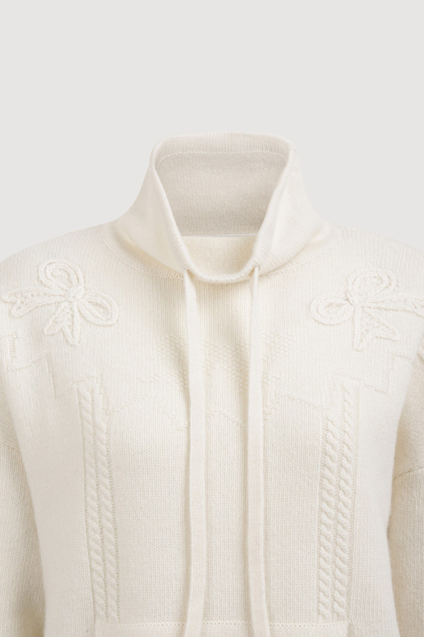 아이보리 색상의 리본 니트 풀오버는 부드러운 메리노 울 100% 소재로 제작되어 포근한 착용감을 선사합니다. 루즈핏으로 편안하게 착용 가능하며, 케이블 패턴과 캥거루 포켓, 리본 디테일이 더해져 캐주얼하면서도 여성스러운 분위기를 연출합니다. 후드 네크라인과 긴 소매 기장으로 가을, 겨울철 따뜻하게 입을 수 있으며, 스트링 조절이 가능하여 핏을 조절할 수 있습니다. 집콕룩, 산책룩, 여행룩 등 다양한 TPO에 활용할 수 있는 베이직하고 미니멀한 스타일의 니트입니다.
