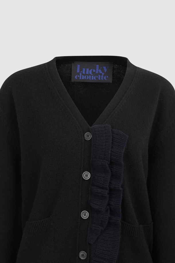 **프릴 브이넥 니트 가디건 (블랙)**

부드러운 촉감의 울, 캐시미어, 나일론 혼방 소재로 제작된 블랙 컬러의 여성용 가을/겨울 니트 가디건입니다. 브이넥 디자인에 앞단 배색 러플 디테일이 더해져 여성스러운 포인트를 더했으며, 넉넉한 루즈핏과 긴 소매 기장으로 편안한 착용감을 선사합니다. 버튼 여밈 방식으로 간편하게 착용할 수 있으며, 데이트룩, 모임룩, 출근룩 등 다양한 TPO에 활용 가능한 베이직 스타일의 아이템입니다. 클래식, 미니멀, 시크한 스타일을 연출하기 좋으며, 스커트와 세트로 착용하여 더욱 세련된 룩을 완성할 수 있습니다.
