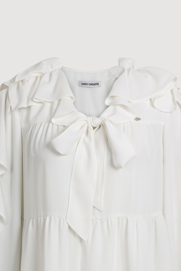 프릴 리본 넥 블라우스는 우아하고 페미닌한 무드를 연출하는 여성 블라우스입니다. 봄, 여름 시즌에 어울리는 얇고 부드러운 촉감의 화이트 컬러 블라우스로, 루즈핏 디자인에 긴 소매 기장으로 제작되었습니다. 리본 넥과 프릴 디테일이 여성스러운 포인트를 더하며, 가벼운 텍스처와 풍성한 실루엣이 특징입니다. 데이트룩, 카페룩, 모임룩 등 다양한 TPO에 클래식, 로맨틱, 미니멀 스타일로 연출하기 좋습니다. 실버 로고와 게더 주름 디테일이 고급스러움을 더합니다.
