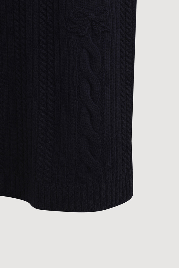 다크 네이비 색상의 리본 니트 스커트입니다. 메리노 울 소재로 제작되어 부드러운 촉감과 따뜻함을 선사하며, 가을/겨울 시즌에 적합합니다. 세미 A라인 핏에 밑단 립조직과 케이블/립조직 패턴이 우아하고 클래식한 분위기를 연출합니다. 허리 부분의 리본 디테일이 여성스러운 포인트를 더하며, 체형 커버에도 효과적입니다. 출근룩과 모임룩 모두 소화 가능한 활용도 높은 맥시 스커트로, 셋업 연출도 가능합니다.
