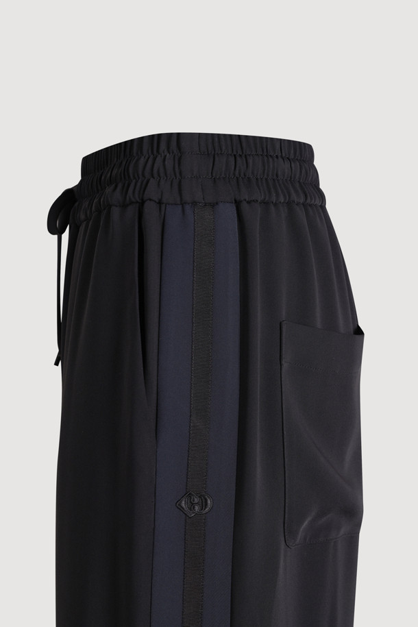 블랙 색상의 사이드 라인 포인트 팬츠입니다. 얇은 두께감으로 여름철에도 시원하게 착용 가능하며, 와이드핏과 부드러운 촉감이 편안한 착용감을 선사합니다. 캐주얼, 미니멀, 스트리트 스타일을 모두 소화할 수 있으며, 동네 마실룩이나 여행룩에 적합합니다. 허리 스트링과 좌측 사이드 포켓, 로고 패치 디테일이 특징입니다. 밴딩 처리된 긴 기장의 와이드핏 바지입니다.
