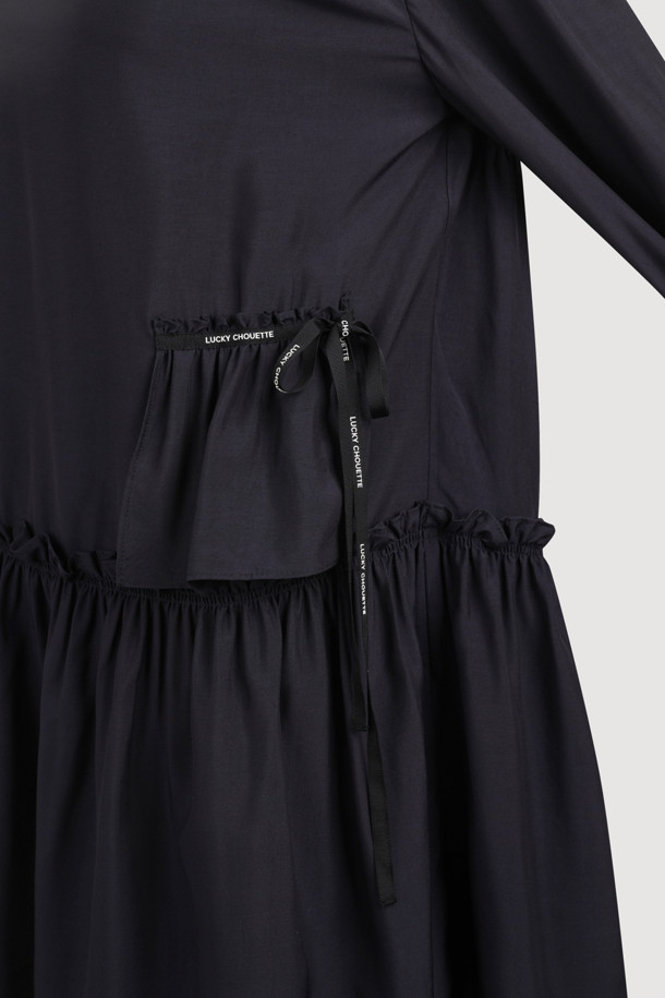 다크 네이비 컬러의 셔링 디테일 라운드넥 원피스입니다. 부드러운 레이온 소재로 제작되어 편안한 착용감을 선사하며, 루즈핏과 플레어 A라인 치마가 자연스러운 실루엣을 연출합니다. 허리선 아래 셔링으로 볼륨감을 더하고, 허리 부분 로고 테이프로 포인트를 주었습니다. 긴 소매와 뒷넥 단추 여밈으로 클래식하면서도 캐주얼한 분위기를 자아내 데이트룩, 모임룩, 또는 미니멀한 스타일을 연출하고 싶은 날에 적합합니다. 사계절 내내 활용 가능한 실용적인 아이템입니다.
