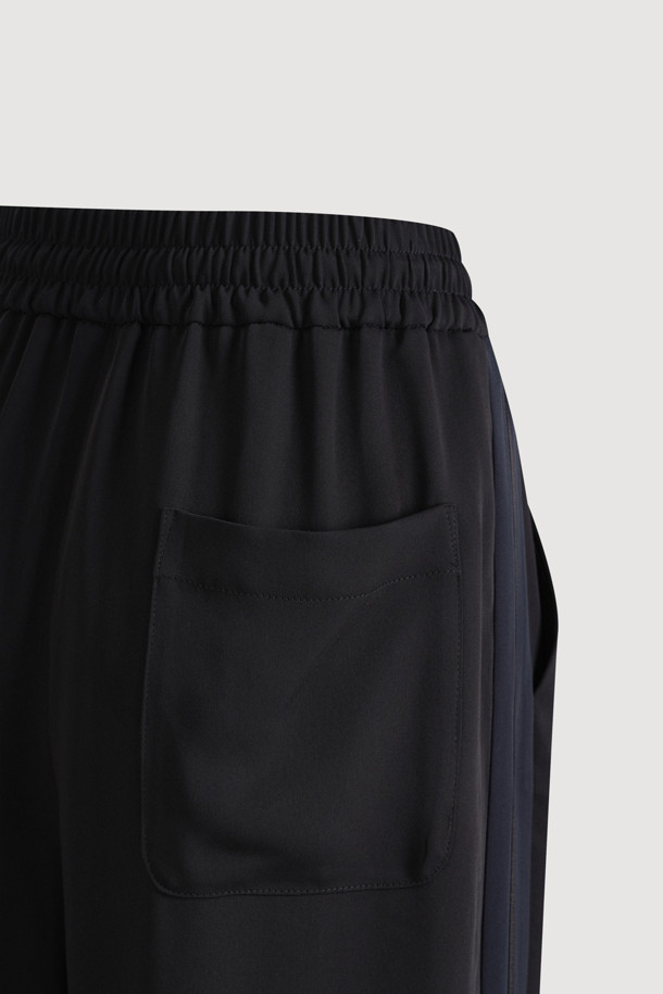 블랙 색상의 사이드 라인 포인트 팬츠입니다. 얇은 두께감으로 여름철에도 시원하게 착용 가능하며, 와이드핏과 부드러운 촉감이 편안한 착용감을 선사합니다. 캐주얼, 미니멀, 스트리트 스타일을 모두 소화할 수 있으며, 동네 마실룩이나 여행룩에 적합합니다. 허리 스트링과 좌측 사이드 포켓, 로고 패치 디테일이 특징입니다. 밴딩 처리된 긴 기장의 와이드핏 바지입니다.
