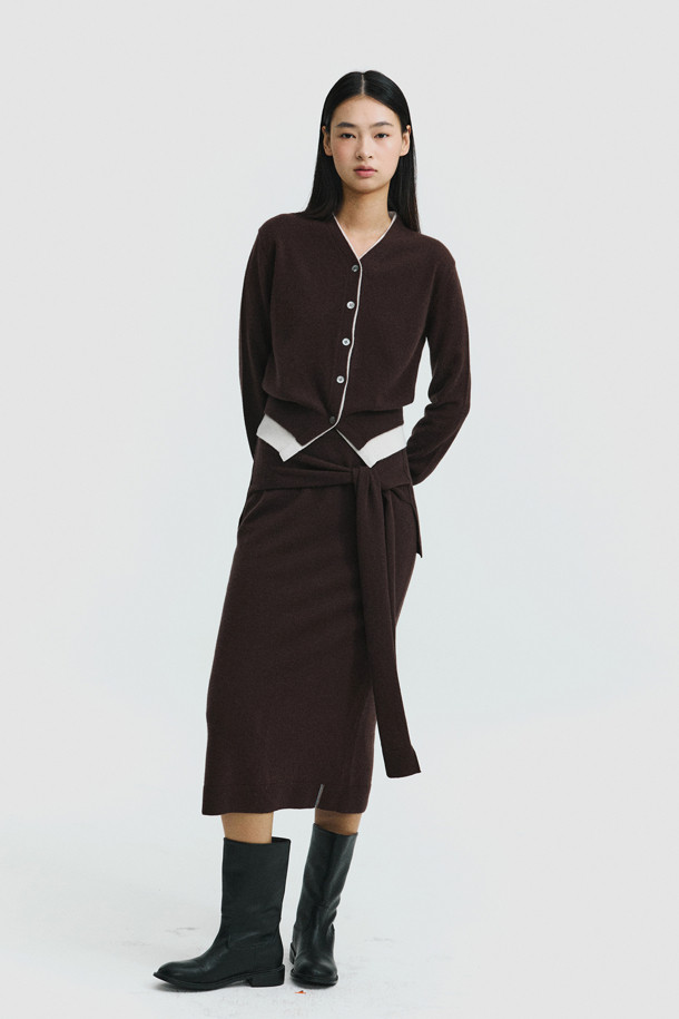 세련된 투톤 배색이 돋보이는 브라운 컬러의 여성 캐시미어 가디건입니다. 몽골산 캐시미어 100% 소재로 제작되어 부드러운 촉감과 뛰어난 보온성을 자랑합니다. V넥 라인과 밑단에 화이트 배색 포인트를 주어 클래식하면서도 세련된 무드를 연출합니다. 레귤러 핏에 얇은 두께감으로 간절기부터 겨울까지 다양하게 활용 가능하며, 버튼 여밈으로 간편하게 착용할 수 있습니다. 데이트룩, 출근룩, 모임룩 등 어떤 TPO에도 잘 어울리는 미니멀 스타일의 가디건입니다.
