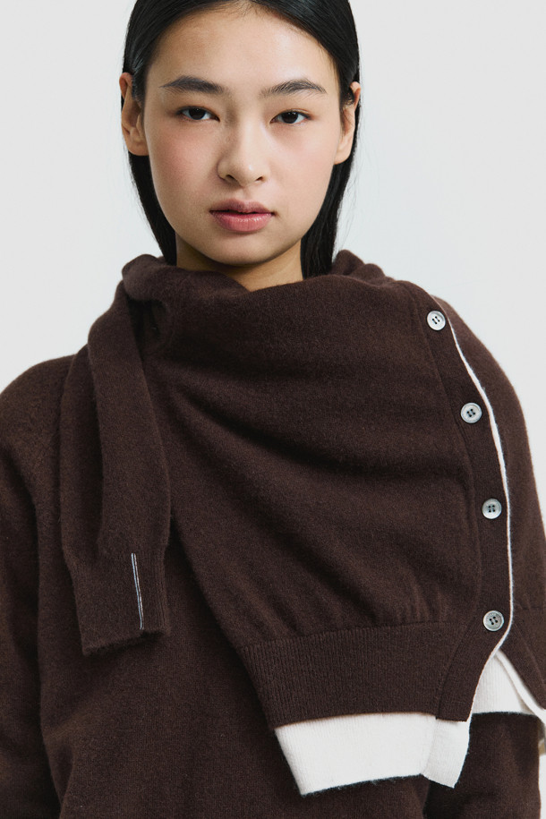 세련된 투톤 배색이 돋보이는 브라운 컬러의 여성 캐시미어 가디건입니다. 몽골산 캐시미어 100% 소재로 제작되어 부드러운 촉감과 뛰어난 보온성을 자랑합니다. V넥 라인과 밑단에 화이트 배색 포인트를 주어 클래식하면서도 세련된 무드를 연출합니다. 레귤러 핏에 얇은 두께감으로 간절기부터 겨울까지 다양하게 활용 가능하며, 버튼 여밈으로 간편하게 착용할 수 있습니다. 데이트룩, 출근룩, 모임룩 등 어떤 TPO에도 잘 어울리는 미니멀 스타일의 가디건입니다.
