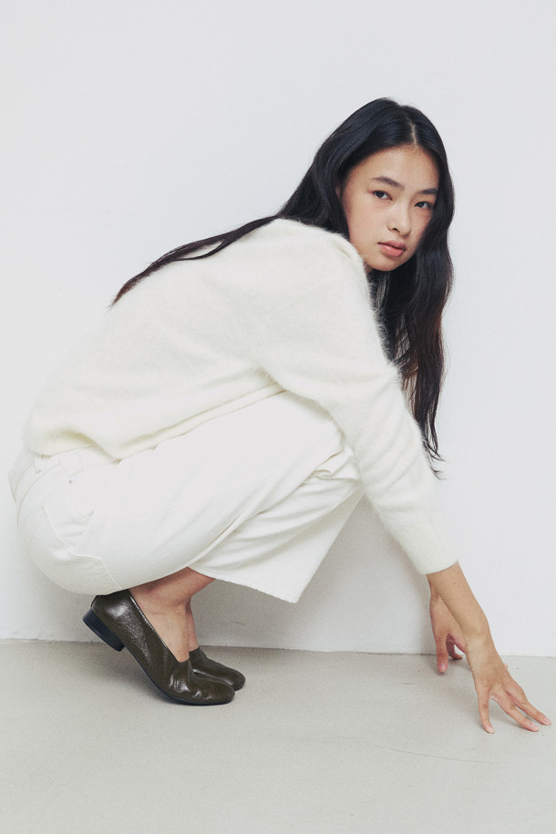 아이보리 컬러의 헤어리 캐시미어 스웨터입니다. 부드러운 촉감의 캐시미어 소재와 브러싱 처리, 기모감으로 포근하고 풍성한 텍스처를 선사합니다. 여유로운 핏과 브이넥 디자인으로 편안하면서도 세련된 스타일을 연출할 수 있습니다. 가을, 겨울 시즌에 어울리는 두꺼운 두께감과 긴 소매 기장으로 따뜻하게 착용 가능하며, 출근룩과 모임룩, 클래식, 미니멀 스타일 모두 소화 가능한 베이직 아이템입니다.
