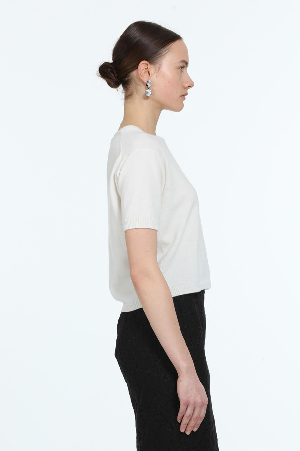 아이보리, 화이트 컬러의 "로고택" 하프슬리브 니트입니다. 부드러운 촉감의 버진울 100% 소재로 제작되어 봄, 여름 시즌에 착용하기 좋습니다. 레귤러핏 라운드넥 디자인에 가디건과 셋업 스타일링이 가능하며, 미니멀하고 베이직한 스타일을 연출합니다. 가슴 위 스몰 로고택 디테일이 특징이며, 일상, 카페룩, 데이트룩 등 다양한 TPO에 활용할 수 있습니다.
