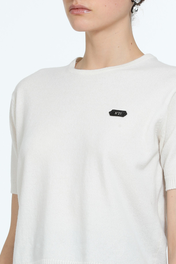 아이보리, 화이트 컬러의 "로고택" 하프슬리브 니트입니다. 부드러운 촉감의 버진울 100% 소재로 제작되어 봄, 여름 시즌에 착용하기 좋습니다. 레귤러핏 라운드넥 디자인에 가디건과 셋업 스타일링이 가능하며, 미니멀하고 베이직한 스타일을 연출합니다. 가슴 위 스몰 로고택 디테일이 특징이며, 일상, 카페룩, 데이트룩 등 다양한 TPO에 활용할 수 있습니다.
