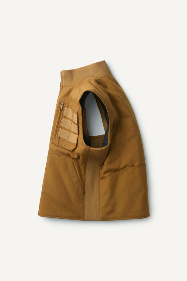 겨울철 일상과 아웃도어 활동에 적합한 헤비듀티 패딩 베스트입니다. 브라운 컬러의 무지 디자인으로, 유틸리티와 스포티한 스타일을 연출합니다. 겉감은 내구성이 뛰어난 코듀라와 나일론 소재를 사용하여 제작되었으며, 두꺼운 두께감으로 보온성을 높였습니다. 고기능성 패딩 충전재와 다수의 포켓, YKK 지퍼, 벨크로 포켓, 웨빙테이프 디테일 등 다양한 기능과 디자인 요소를 갖추었습니다. 내구성과 내마모성이 뛰어나며, 사이드 립 배색으로 포인트를 주어 세련된 겨울 데일리룩과 여행룩을 완성합니다.
