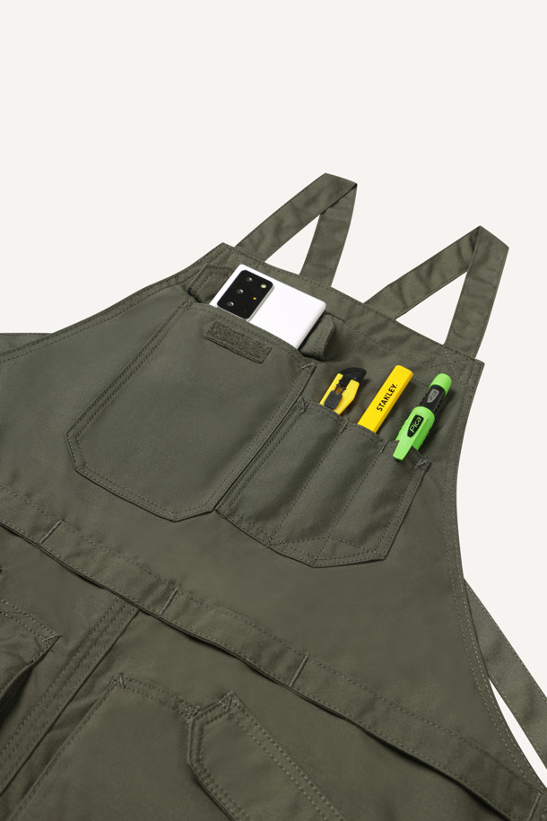 워크 툴 에이프런은 남녀 공용으로 제작되었으며, 카키와 올리브 두 가지 색상으로 만나볼 수 있습니다. 내구성이 뛰어나고 수납성이 뛰어난 워크웨어 에이프런으로, 나일론과 코듀라 소재를 사용하여 흡습, 속건, 내마모 기능까지 갖췄습니다. 가슴 포켓 4개, 하단 포켓 4개, 펜 포켓 등 넉넉한 수납공간을 제공하며, 벨크로, 몰리시스템, X자형 어깨끈으로 디자인에 포인트를 더했습니다.  길이 조절, 가랑이 트임, 패치 부착 가능 등 디테일한 기능성으로 워크샵룩, 캠핑룩, 가을 나들이룩, 워크웨어, 고프코어, 미니멀 스타일을 즐기는 분들께 적합합니다.
