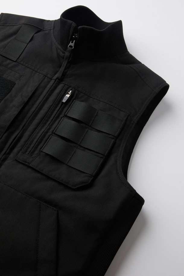 헤비듀티 패딩 베스트는 혹독한 겨울 날씨에도 끄떡없는 보온력을 제공하는 남녀 공용 아우터입니다. 블랙 컬러의 무지 디자인에, 스포티와 밀리터리 스타일을 결합하여 일상 및 아웃도어 활동에 모두 적합합니다. 튼튼한 코듀라와 나일론 소재를 사용하여 내구성과 내마모성을 높였으며, 두꺼운 두께감과 부드러운 촉감이 특징입니다. YKK 스냅/지퍼, 웨빙 테이프 디테일, 벨크로 포켓, 다중 포켓 구성, 고기능성 패딩 충전재 등이 적용되어 뛰어난 기능성을 자랑합니다. 스포티, 워크웨어, 미니멀 스타일을 추구하는 분들께 겨울 데일리룩과 캠핑룩에 완벽한 선택이 될 것입니다.
