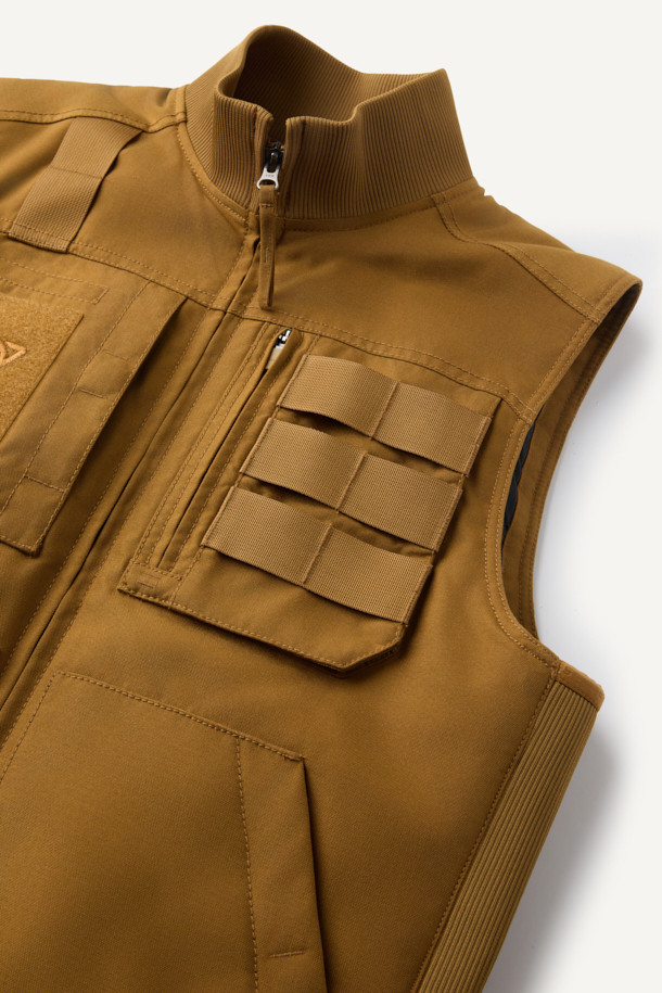 겨울철 일상과 아웃도어 활동에 적합한 헤비듀티 패딩 베스트입니다. 브라운 컬러의 무지 디자인으로, 유틸리티와 스포티한 스타일을 연출합니다. 겉감은 내구성이 뛰어난 코듀라와 나일론 소재를 사용하여 제작되었으며, 두꺼운 두께감으로 보온성을 높였습니다. 고기능성 패딩 충전재와 다수의 포켓, YKK 지퍼, 벨크로 포켓, 웨빙테이프 디테일 등 다양한 기능과 디자인 요소를 갖추었습니다. 내구성과 내마모성이 뛰어나며, 사이드 립 배색으로 포인트를 주어 세련된 겨울 데일리룩과 여행룩을 완성합니다.
