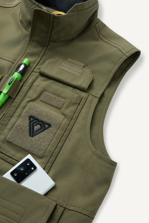 헤비듀티 베스트 V2는 작업용 또는 일상복으로 활용 가능한 남녀 공용 베스트입니다. 카키와 올리브 두 가지 색상으로 출시되었으며, 사계절 착용 가능한 두꺼운 두께감의 코듀라, 나일론 혼방 소재로 제작되었습니다. 밀리터리, 워크웨어 스타일을 기반으로 무지 패턴과 레귤러핏 디자인을 적용했으며, 총 15개의 포켓, 몰리 시스템, 벨크로 패치 부착 가능, YKK 지퍼, 제전성 안감 등 뛰어난 기능성을 자랑합니다. 캠핑룩, 출근룩, 워크웨어, 캐주얼, 고프코어 스타일 연출에 적합합니다.
