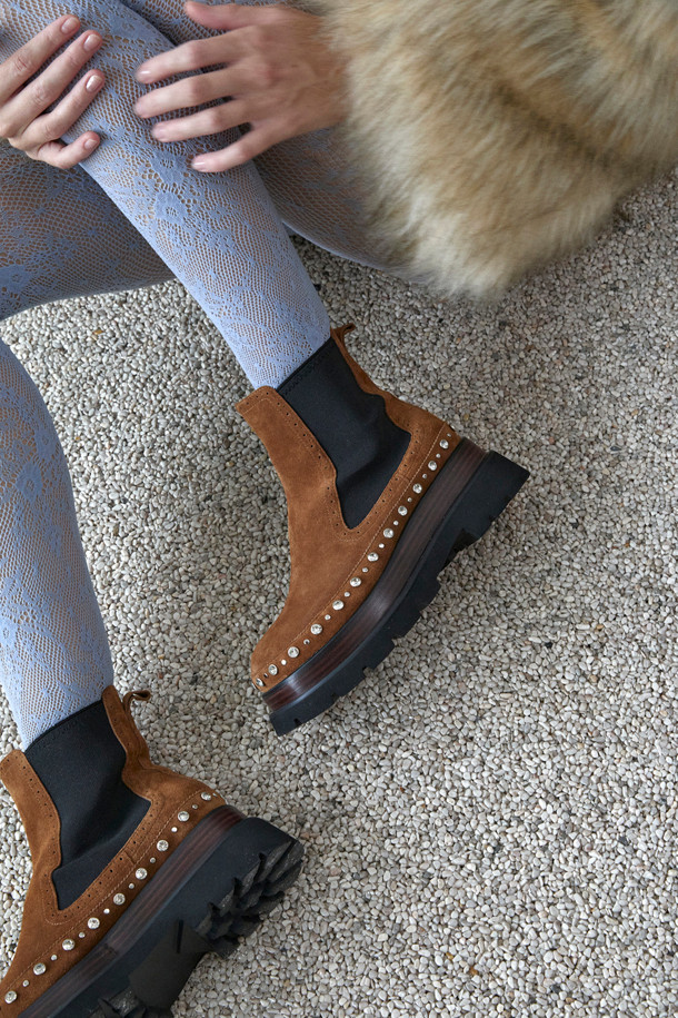 세련된 무드를 연출하는 스터드 앵클 부츠(브라운)입니다. 부드러운 소가죽 소재로 제작되어 고급스러운 질감을 자랑하며, 측면 밴딩 디테일이 편안한 착화감을 선사합니다. 클래식한 첼시부츠 실루엣에 스터드와 보석 장식이 더해져 유니크한 포인트를 더합니다. 로우힐 디자인으로 활동성을 높였으며, 출근룩과 모임룩 등 다양한 TPO에 활용 가능합니다. 미니멀, 시크, 클래식 스타일을 즐겨 입는 여성분들께 추천합니다.
