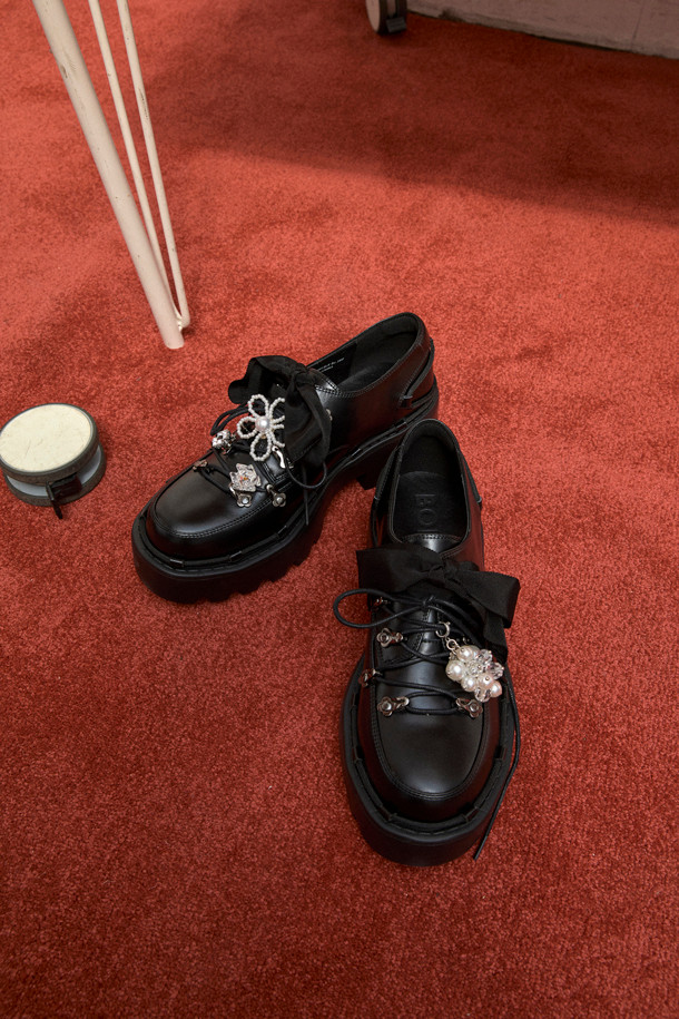 **Shoe lace 로퍼(black)**

소가죽 소재의 블랙 컬러 Shoe lace 로퍼입니다. 일상에서 편안하게 착용하기 좋은 플랫 굽 디자인으로, 캐주얼하면서도 여성스러운 분위기를 연출합니다. 리본 신끈과 고리 장식, 청키한 디자인이 돋보이며, 출근룩이나 모임룩에 미니멀한 스타일로 코디하기 좋습니다.
