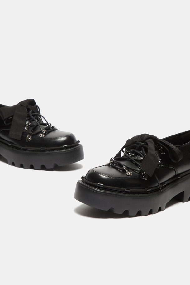 **Shoe lace 로퍼(black)**

소가죽 소재의 블랙 컬러 Shoe lace 로퍼입니다. 일상에서 편안하게 착용하기 좋은 플랫 굽 디자인으로, 캐주얼하면서도 여성스러운 분위기를 연출합니다. 리본 신끈과 고리 장식, 청키한 디자인이 돋보이며, 출근룩이나 모임룩에 미니멀한 스타일로 코디하기 좋습니다.
