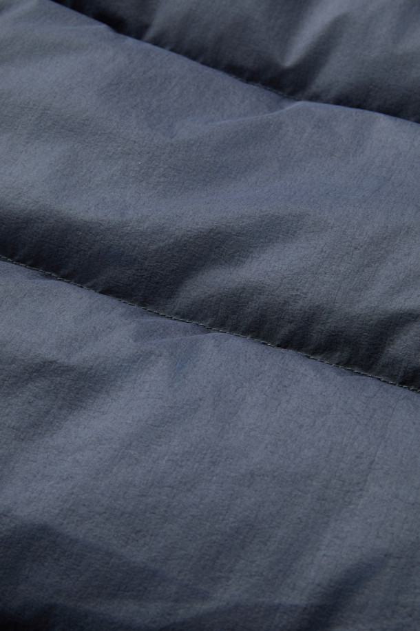 **HANKALEX(헝카렉스) 다이드 덕 다운**은 빈티지한 스타일의 네이비 컬러 덕 다운 아우터입니다. 겨울철 보온성을 책임지는 두꺼운 두께감과 루즈핏으로 편안한 착용감을 선사합니다. 발수 기능과 PU 필름 코팅으로 생활 방수가 가능하며, 가먼트 다잉 처리로 특유의 빈티지한 멋을 더했습니다. 소매 시보리 디테일과 전면 지퍼 포켓으로 실용성을 높였으며, 출근룩과 여행룩, 캐주얼, 미니멀, 클래식 스타일 모두 소화 가능한 활용도 높은 아이템입니다.
