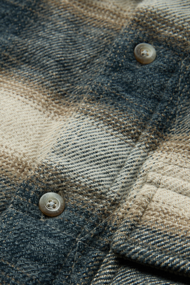 "체크 퀼팅 아우터 셔츠"는 빈티지 스타일의 코듀로이 소재 아우터 셔츠입니다. 부드러운 촉감과 적당한 두께감으로 간절기부터 초겨울까지 착용하기 좋으며, 3M 신슐레이트 충전재를 사용하여 뛰어난 보온성을 제공합니다. 네이비와 베이지 두 가지 컬러로 출시되었으며, 셔츠형 디자인에 퀼팅 디테일과 가슴 1개, 허리 2개의 포켓, 칼라 부분의 코듀로이 배색이 돋보입니다. 세미 오버핏으로 제작되어 편안하면서도 스타일리시하게 연출할 수 있으며, 스냅 버튼으로 간편하게 여밀 수 있습니다. 출근룩과 모임룩은 물론 클래식, 캐주얼, 미니멀 등 다양한 스타일 연출에 활용 가능한 아이템입니다.
