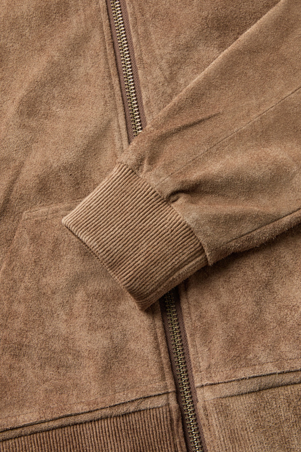 A LEATHER (레더) 집 후디는 부드러운 소가죽, 레이온, 면 혼방 소재로 제작된 남녀 공용 가죽 후드 집업입니다. 가을, 겨울 시즌에 어울리며, 캐주얼, 스트릿, 미니멀 스타일을 연출하기 좋습니다. 크롭 기장의 레귤러핏으로, 스웨트셔츠 봉제 기법과 소매 및 밑단 가죽 립 처리, 파워 네트 삽입을 통한 신축성 구현으로 활동성을 높였습니다. 넉넉한 두께감과 부드러운 촉감, 무지 디자인이 특징이며, 여행룩 또는 캠핑룩에 활용하기 좋습니다. 안감은 레이온/면 혼방으로 제작되어 편안한 착용감을 선사합니다.
