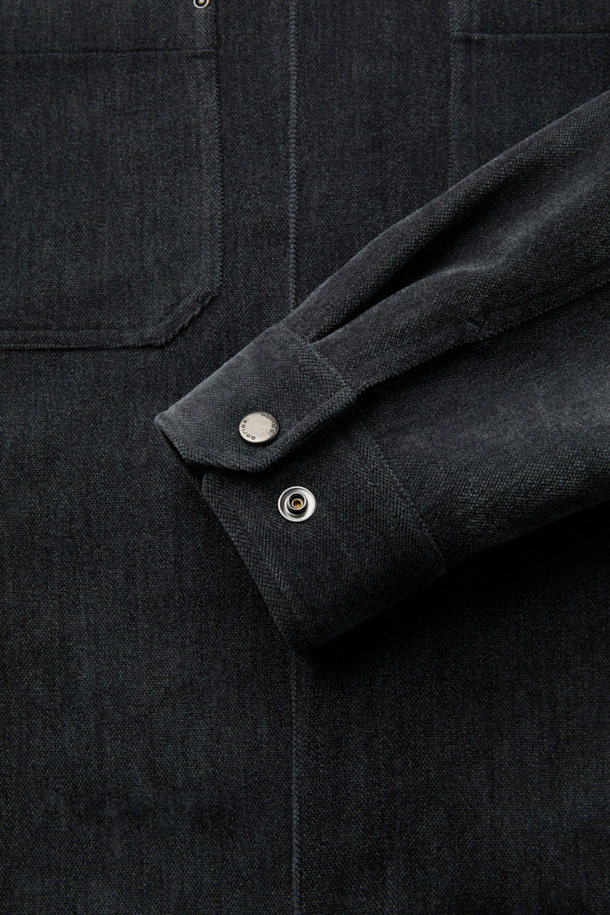 다크 그레이 컬러의 벨루어 아우터 셔츠입니다. 부드러운 셔닐 소재와 폴리에스테르 혼방으로 제작되어, 가을과 겨울에 포근하게 착용할 수 있습니다. 셔츠 칼라와 오버핏 실루엣, 드롭 숄더 디자인으로 미니멀하고 세련된 스타일을 연출합니다. 가슴 요크선, 아웃포켓, 허리 포켓 디테일이 돋보이며, 은은한 광택감과 드레이프성이 특징입니다. 출근룩과 모임룩, 다양한 스타일링에 활용 가능한 아이템입니다.
