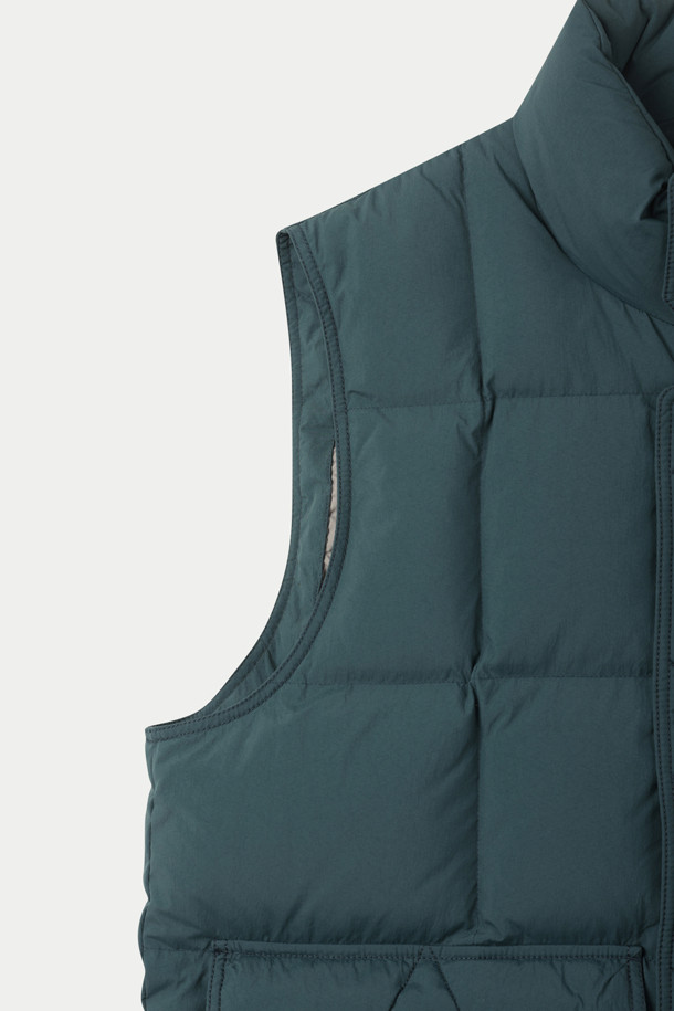다크 그린 컬러의 블록 다운 베스트는 가을, 겨울철 일상 및 아웃도어 활동에 적합합니다. 80:20 RDS MUSCOVY 덕다운 충전재를 사용하여 보온성을 높였으며, 방풍 코팅과 밑단 스트링 조절 기능으로 외부 환경으로부터 몸을 보호합니다. 루즈핏으로 제작되어 편안한 착용감을 제공하며, 클래식, 캐주얼, 미니멀 스타일을 모두 소화할 수 있습니다. 이중 구조 핸드포켓과 넥라인 스트랩 디테일이 돋보이며, 경량 설계로 활동성을 더했습니다. 캠핑룩, 등산룩 연출에 활용하기 좋습니다.
