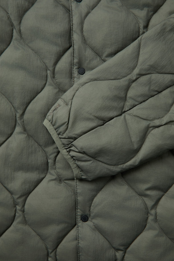 F/CE X TAION(에프씨이 X 테이온) 패커블 이너 덕 다운 재킷은 겨울철 일상룩과 여행, 캠핑룩에 적합한 남녀 공용 아우터입니다. 미니멀하고 캐주얼한 스타일을 연출하며, 퀄팅 패턴과 크롭 기장이 특징입니다. 800 필파워 화이트 덕다운 충전재와 발수 처리, 생활 방수 기능을 갖춰 보온성을 높였습니다. 
버튼 여밈 방식이며, 부드러운 촉감의 나일론 소재와 긴 소매 기장으로 제작되었습니다. 보관용 파우치가 포함되어 휴대 및 보관이 용이합니다.
카키와 올리브 두 가지 색상으로 출시되었습니다.
