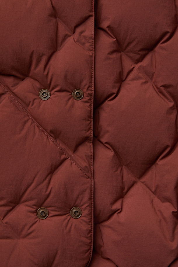 CMF 우븐 다운 베스트는 가을, 겨울철 일상 및 아웃도어 활동에 적합한 남녀 공용 베스트입니다. 브라운 컬러의 퀼팅 패턴과 크롭 기장으로 캐주얼, 스포티, 미니멀 스타일을 연출할 수 있습니다. CMF WOVEN 기술을 적용하여 다운팩 없이 X자 구조로 직조되었으며, 다운 90%, 페더 10% (700FP)의 안감과 다운 본딩 처리로 보온성을 높였습니다. 얇고 가벼운 나일론, 폴리우레탄 소재에 넉넉한 두께감과 부드러운 촉감, 사선 포켓 디자인이 특징입니다. 캠핑룩으로 활용하기 좋으며 스냅 여밈 방식으로 편안하게 착용할 수 있습니다.
