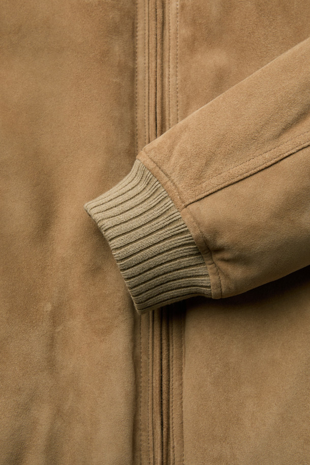 베이지 컬러의 스웨이드 다운 점퍼입니다. 간절기와 초겨울에 적합하며, 클래식하고 미니멀한 스타일을 연출합니다. 부드러운 스웨이드 소재와 두꺼운 두께감으로 포근함을 더하고, 구스다운 충전재를 사용하여 보온성을 높였습니다. 스탠드넥 구조와 니트 시보리 디테일이 돋보이며, 안감과 다운백 분리 설계로 편안함을 제공합니다. 투웨이 지퍼와 긴 소매 기장으로 출근룩에 활용하기 좋습니다.
