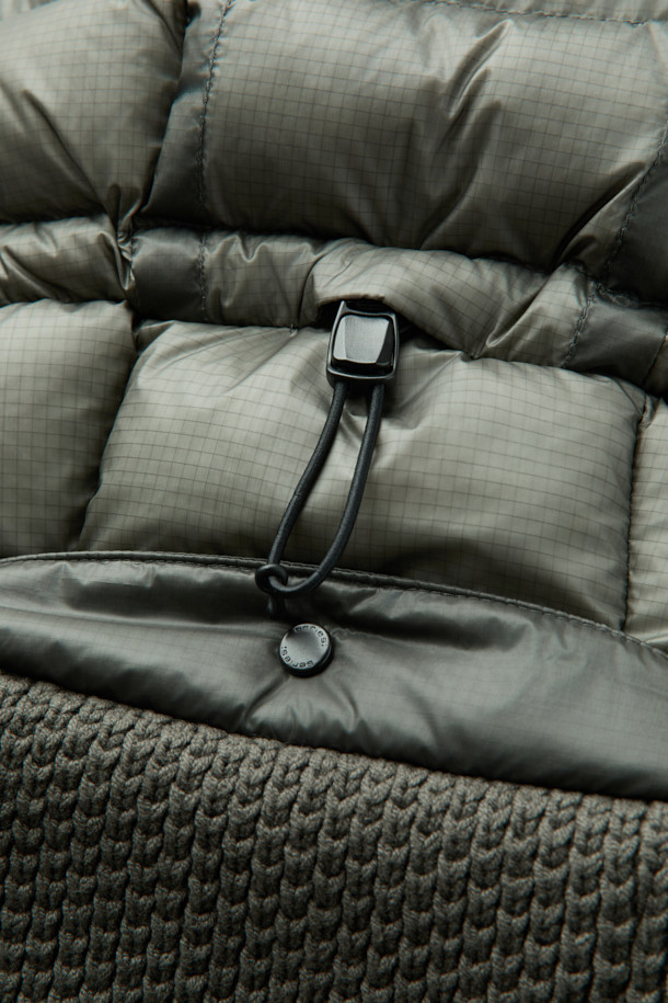 세련된 니트 하이브리드 아우터 점퍼입니다. 캐주얼, 미니멀, 클래식 스타일을 아우르며, 일상과 출근룩에 모두 잘 어울립니다. 카키 및 올리브 색상으로 출시되어 겨울철 스타일링에 포인트를 더합니다. 초경량 나일론과 니트 소재의 조합으로 뛰어난 착용감과 보온성을 제공하며, 덕다운 충전재, 방풍, 발수 기능, 탈부착 후드, 하이브리드 디자인 등 다양한 특징을 갖췄습니다. 레귤러핏에 집업 스타일로 편안함과 활동성을 동시에 잡았습니다.
