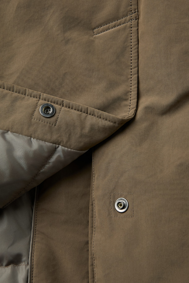 겨울철 일상과 출근룩, 여행룩에 모두 잘 어울리는 구스 코트입니다. 카키와 브라운 두 가지 색상으로 출시되어 미니멀하고 베이직한 스타일을 연출합니다. 롱 기장에 세미 오버핏으로 편안한 착용감을 선사하며, 버튼 여밈 방식으로 간편하게 입고 벗을 수 있습니다. 나일론과 폴리에스테르 혼방 소재로 제작되어 두꺼운 두께감과 부드러운 촉감을 자랑하며, 드롭숄더 디자인과 퀼팅 안감, 생활 방수 및 방풍 기능을 갖춰 보온성을 높였습니다. 
